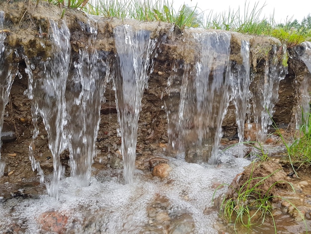 Небольшой водопад. Текущая вода размывает почву.