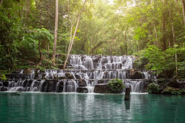 Foto piccola cascata con acqua che spruzza e cade sulle rocce nella foresta su una brillante cascata soleggiata sam lan