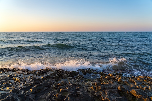 Небольшие волны на скалистом берегу моря утром