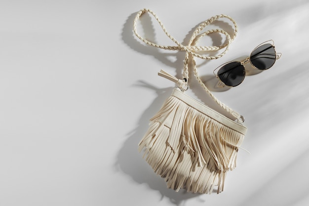 Small white bag with fringe and sunglass. Summer Vacation concept.