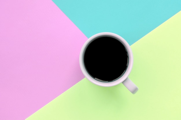 Small white coffee cup on texture of fashion pastel pink, blue and lime colors paper