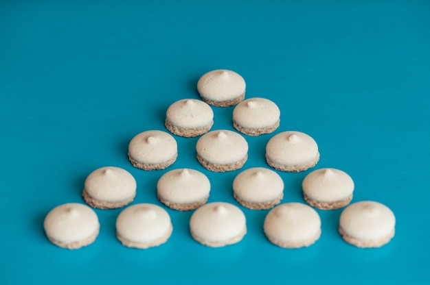 Photo small white cookies are arranged in the form of a triangle on blue