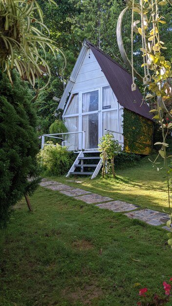 Photo a small white cottage in the woods with a small porch and steps leading to the front door