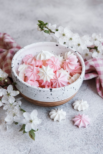 Photo small white and pink meringues in the ceramic bowl on concrete surface