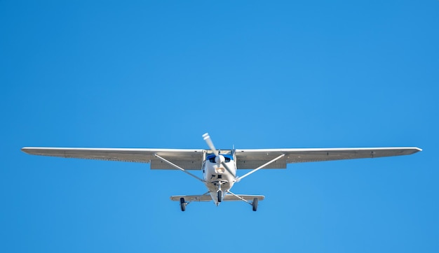 写真 着陸前に澄んだ空を飛ぶセスナ プロペラの青い縞模様の小さな白い飛行機