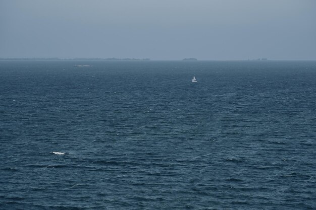 A small white sailboat is sailing on the big blue Volga River