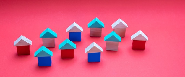 Small wooden blocks house models with roofs on red background