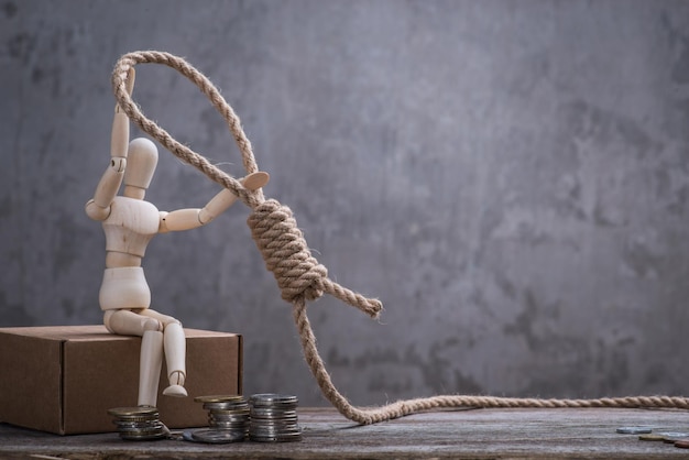 Small wooden dummy sitting with hangman's noose and coins