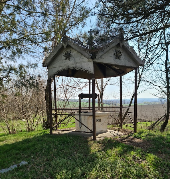 A small wooden gazebo with a tree in the background.