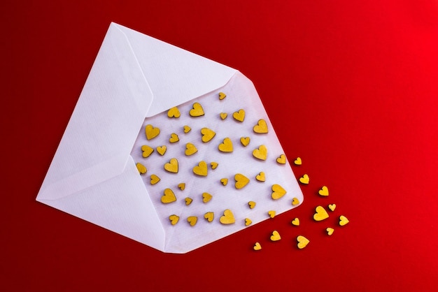 Small wooden hearts fly out of a white envelope on a red background Valentines Day