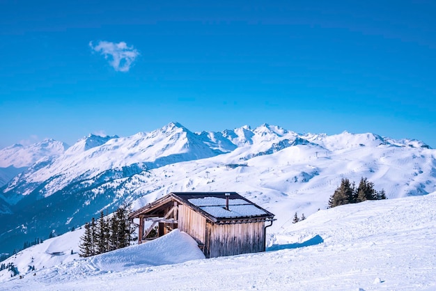 Small wooden house on snowy mountain against blue sky