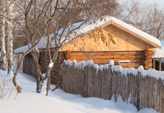 雪に覆われた森の小さな木製の丸太小屋