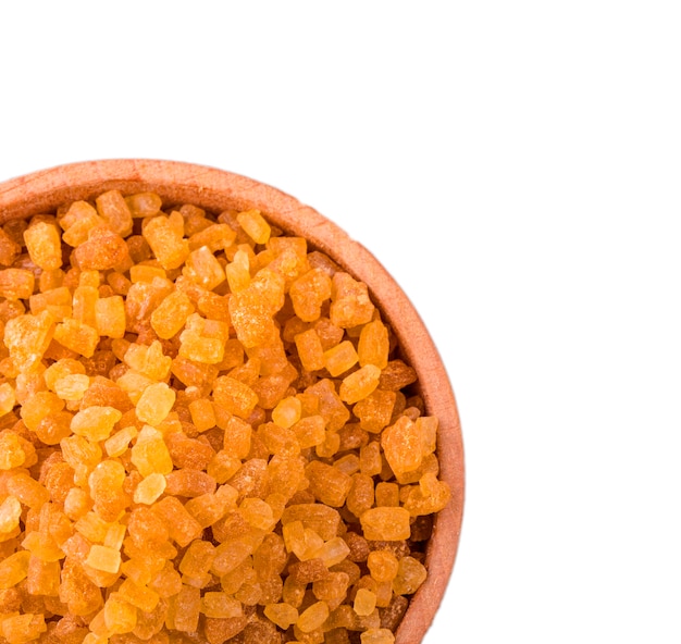 Small wooden round bowl full of brown cane sugar on white background