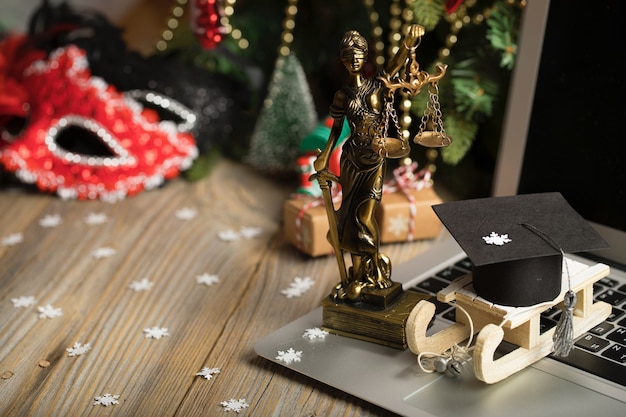 Photo small wooden sleigh with graduate cap on it placed on a laptop closeup