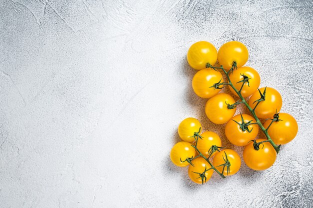 Small yellow cherry tomato on a kitchen table. White table . Top view.  