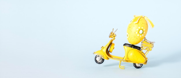 Photo small yellow figurine of motorbike with yellow and white easter egg