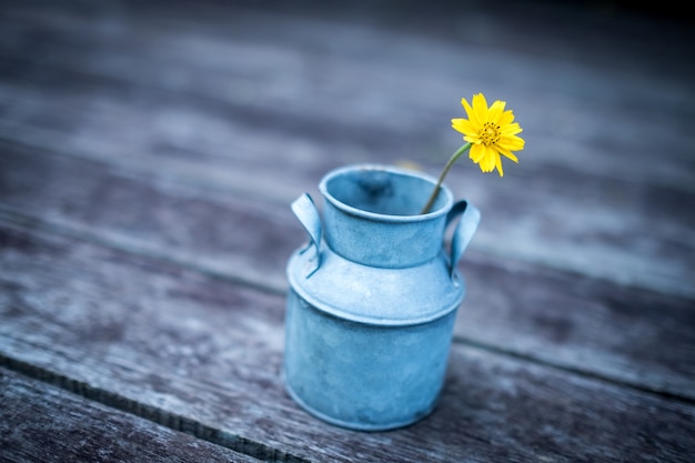 缶の中の小さな黄色の花、木の床に立っている