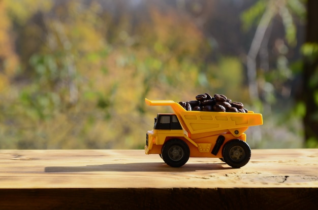 작은 노란색 장난감 트럭에는 갈색 커피 원두가 들어 있습니다.