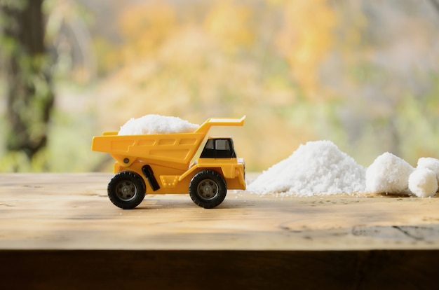 A small yellow toy truck is loaded with a stone of white salt t