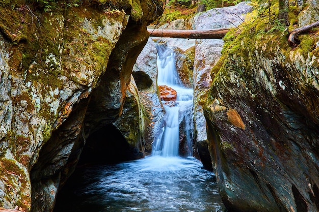 Smalle kloof op ooghoogte naar waterval die naar beneden raast met bemoste rotsen