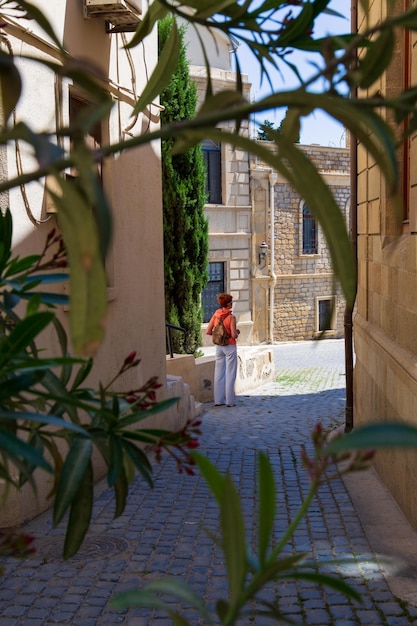 Smalle straat in de oude stad tussen gebeeldhouwde stenen gebouwen met wandelende vrouwelijke toerist Baku Azerbeidzjan