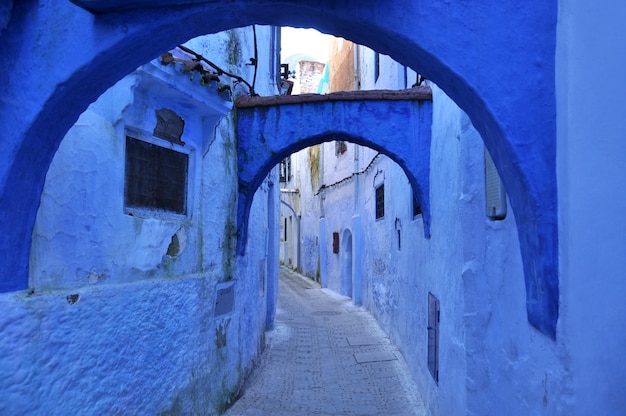 Smalle straat met blauwe muren en bogen in de Marokkaanse stad Chefchaouen