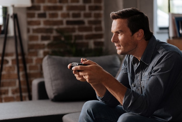 Smart analytical handsome man carefully developing his strategy while using special gamepad