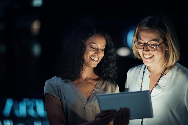 Smart apps made their night productive Shot of two colleagues using a digital tablet together during a late night at work