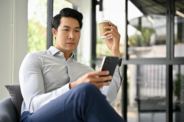 Умный азиатский бизнесмен проверяет деловую почту на своем смартфоне