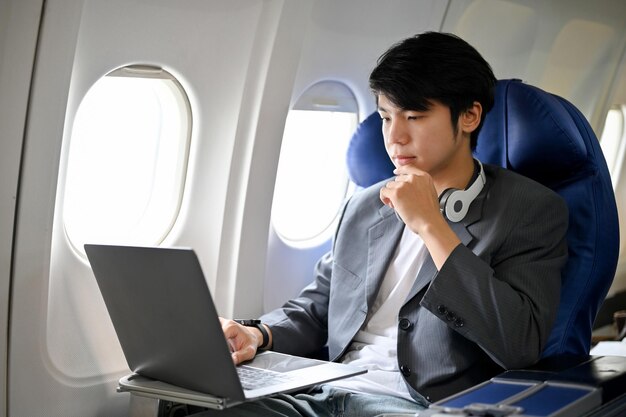 Smart asian businessman concentrating working on laptop during\
the flight on his private jet