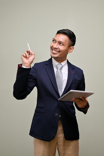 Smart Asian businessman holding his tablet and pointing tablet's pen up on empty space