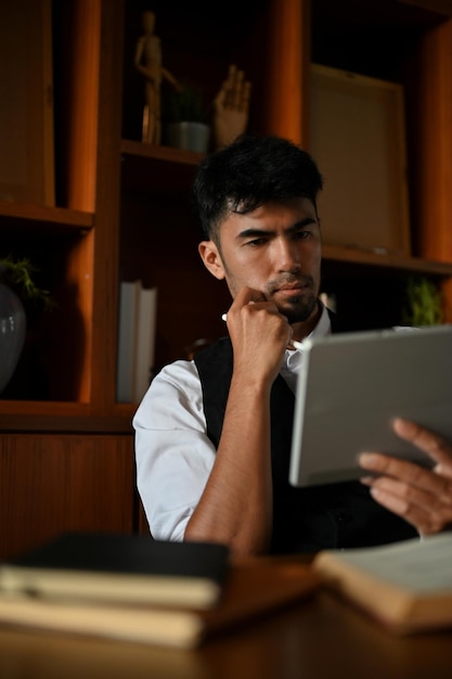 Умный азиатский бизнесмен или исполнительный менеджер-мужчина за своим офисным столом с помощью планшета