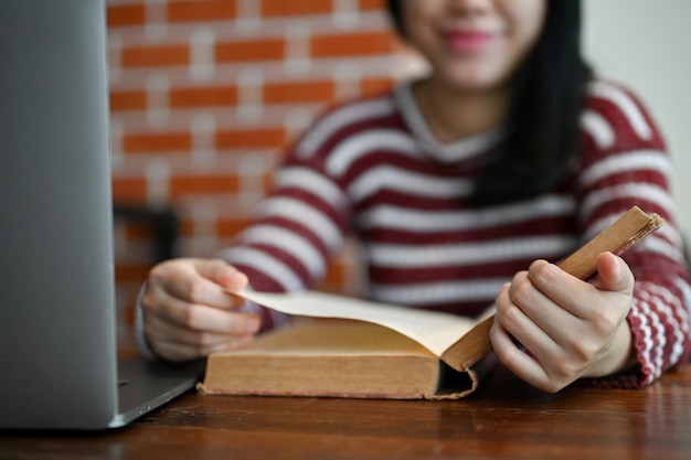 Умная азиатская студентка изучает информацию об учебнике, читая книгу