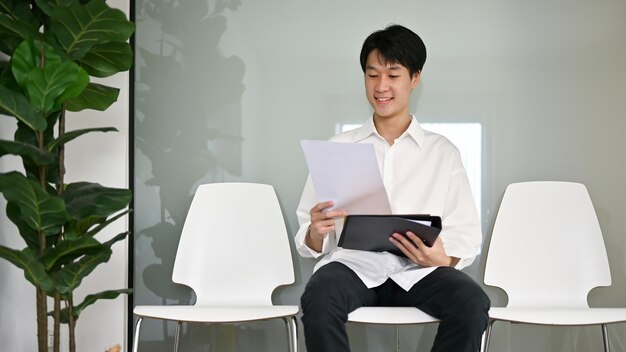 Photo smart asian male candidate sits in a waiting room waiting for a job interview