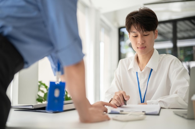 A smart Asian male office worker working on a project with a female colleague in the office