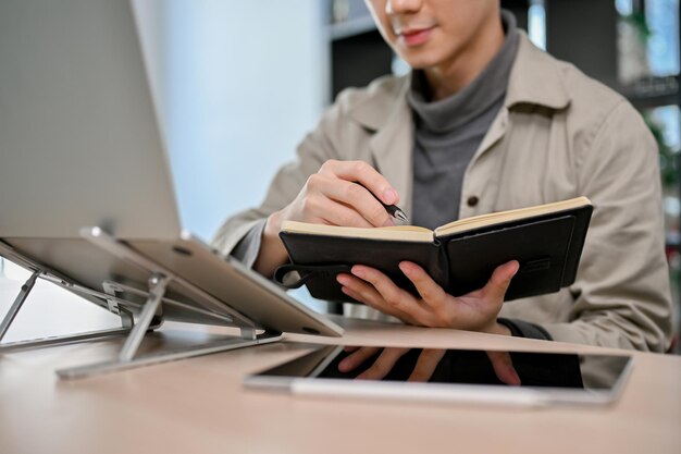 Smart Asian male programmer or web developer concentrating on his task taking notes