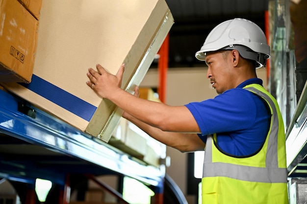 Smart asian male warehouse worker working in warehouse checking\
inventory in parcel