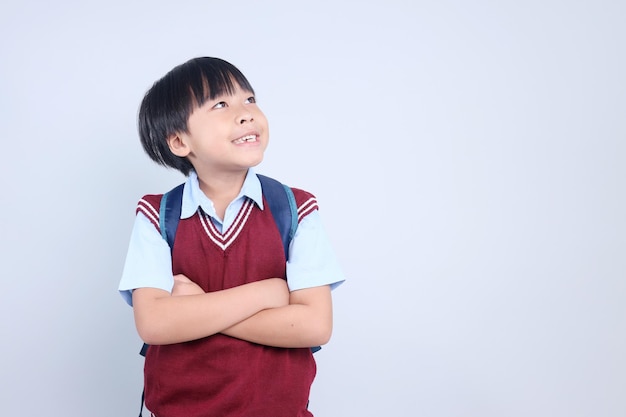 Photo smart asian schoolboy wearing backpack and looking up to empty space