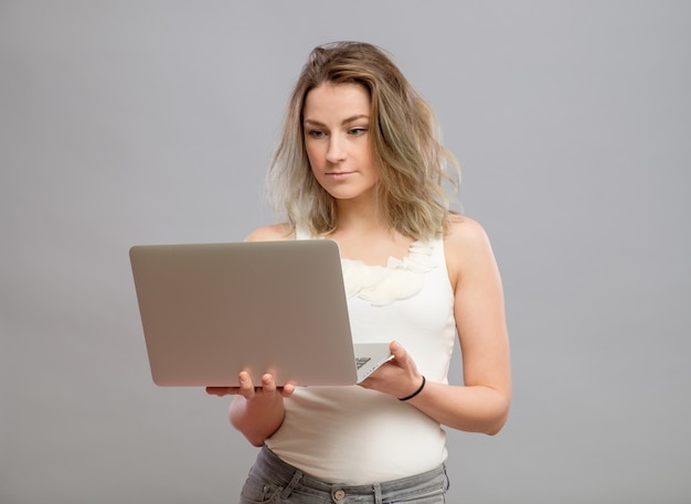 Smart beautiful young girl using laptop pc computer isolated on gray background