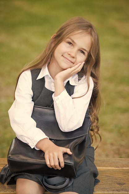 Photo smart beauty happy child smile sitting on bench little girl hold bag wearing uniform school fashion beauty salon back to school formal education september 1 knowledge day