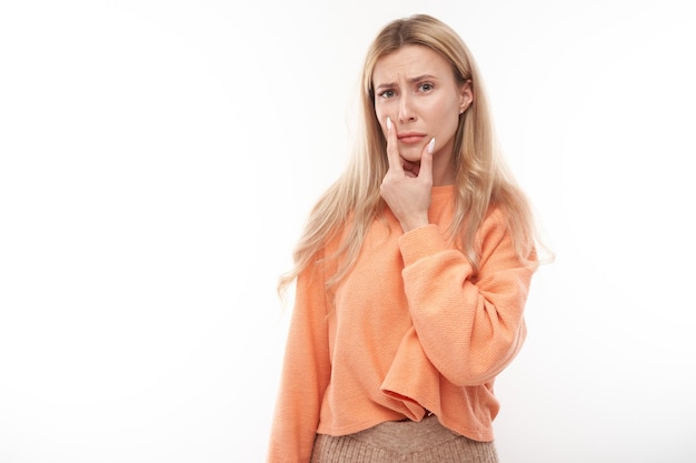 Smart blonde girl in casual holding chin thinks doubts makes decision isolated on white studio background