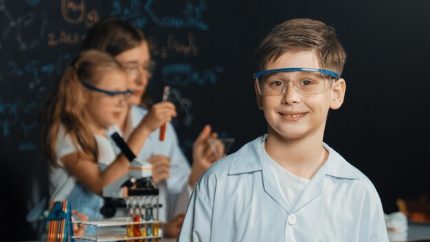 Smart boy crossing arms while teacher and frien doing experiment erudition