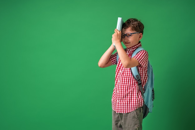 Smart boy with glasses hides his face behind a book