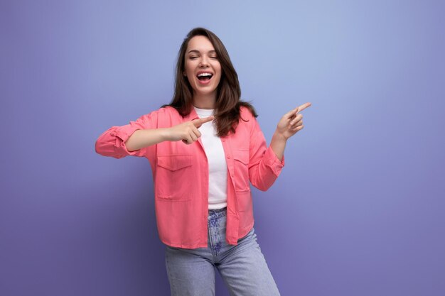 Smart brunette lady casual style pointing finger at space for information on studio background