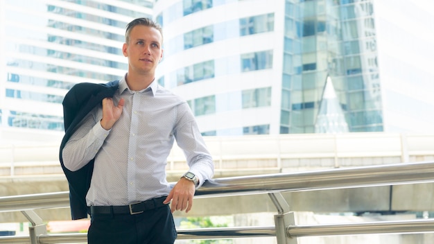 Smart business uomo sicuro stand allo spazio pubblico all'aperto con un edificio moderno