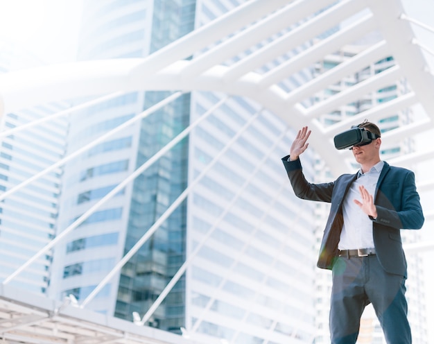 Smart businessman in a suit wear vr goggles with city town background.