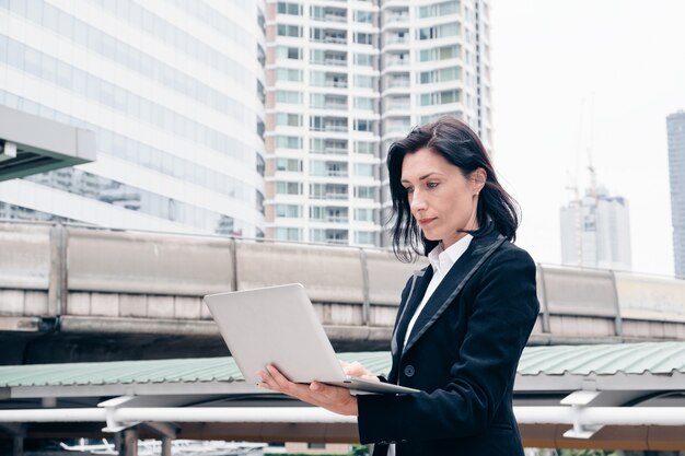 Una donna d'affari intelligente sta usando il laptop in città