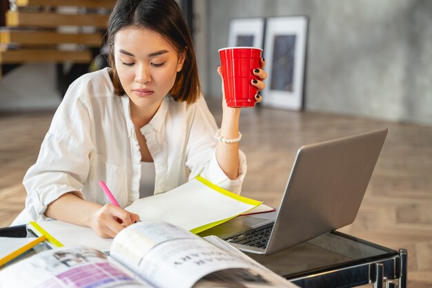 彼女の職場でコーヒーを飲むスマートな忙しい女性