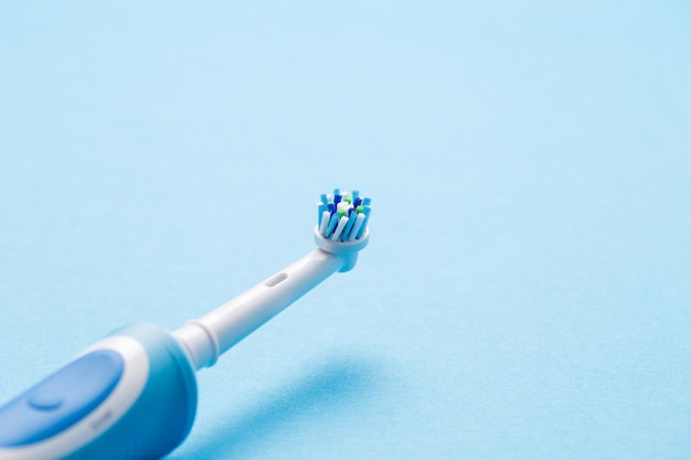 Smart electric toothbrush on a blue wall close-up. Nozzle for brushing teeth.