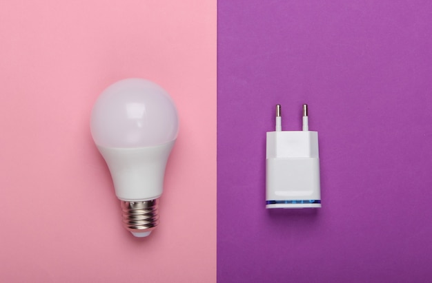 Smart energy-saving light bulb with a charger on a pink-purple background. Top view